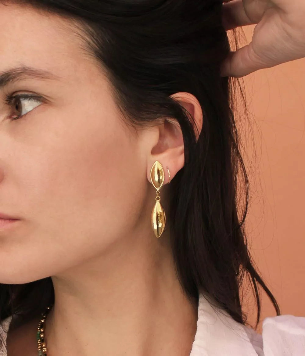 boucles à pendants forme de gouttes dorées à puce sur  oreille femme qui tient ses cheveux