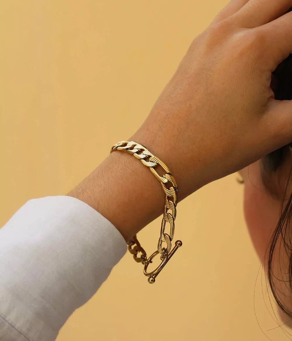 bracelet doré maille figaro sur poignet femme femme qui se tient les cheveux