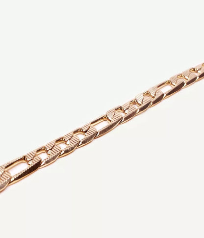 gros plan sur bracelet doré maille figaro sur fond blanc