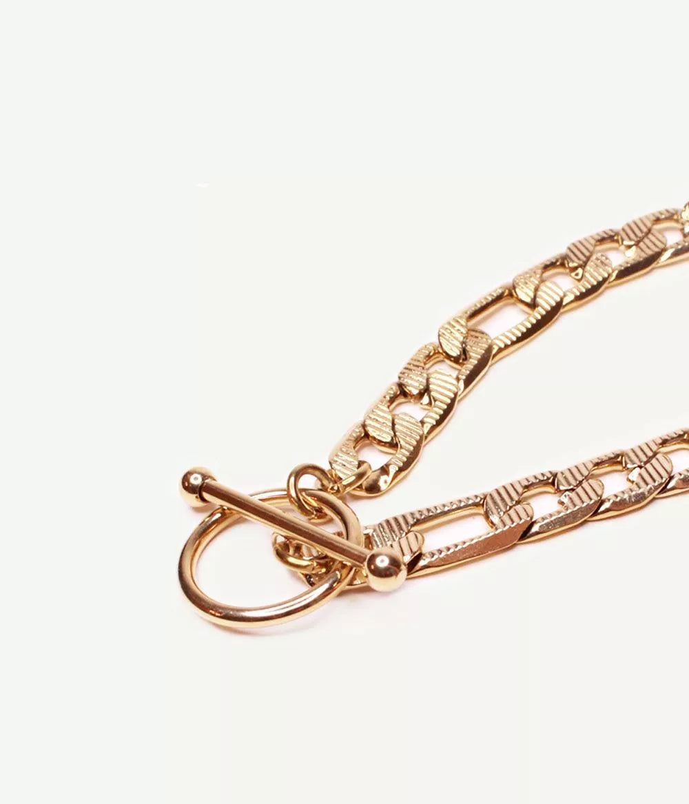 gros plan sur attache tige dans un cercle du bracelet doré maille figaro sur fond blanc 