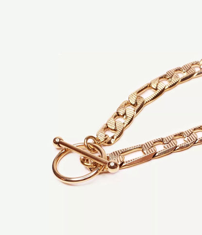 gros plan sur attache tige dans un cercle du bracelet doré maille figaro sur fond blanc 