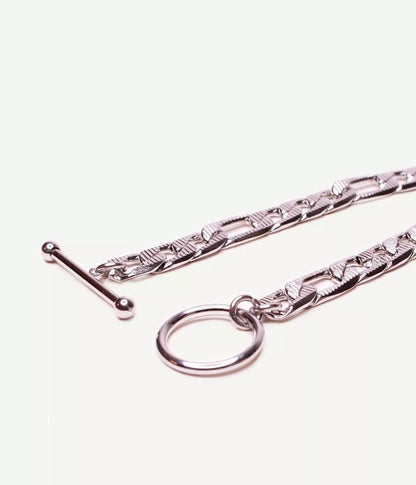 gros plan sur attache tige dans un cercle ouvert du bracelet argenté maille figaro sur fond blanc 