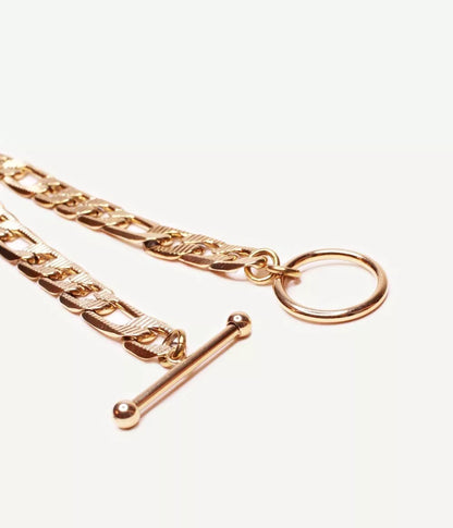 gros plan sur attache tige dans un cercle ouvert du bracelet doré maille figaro sur fond blanc 