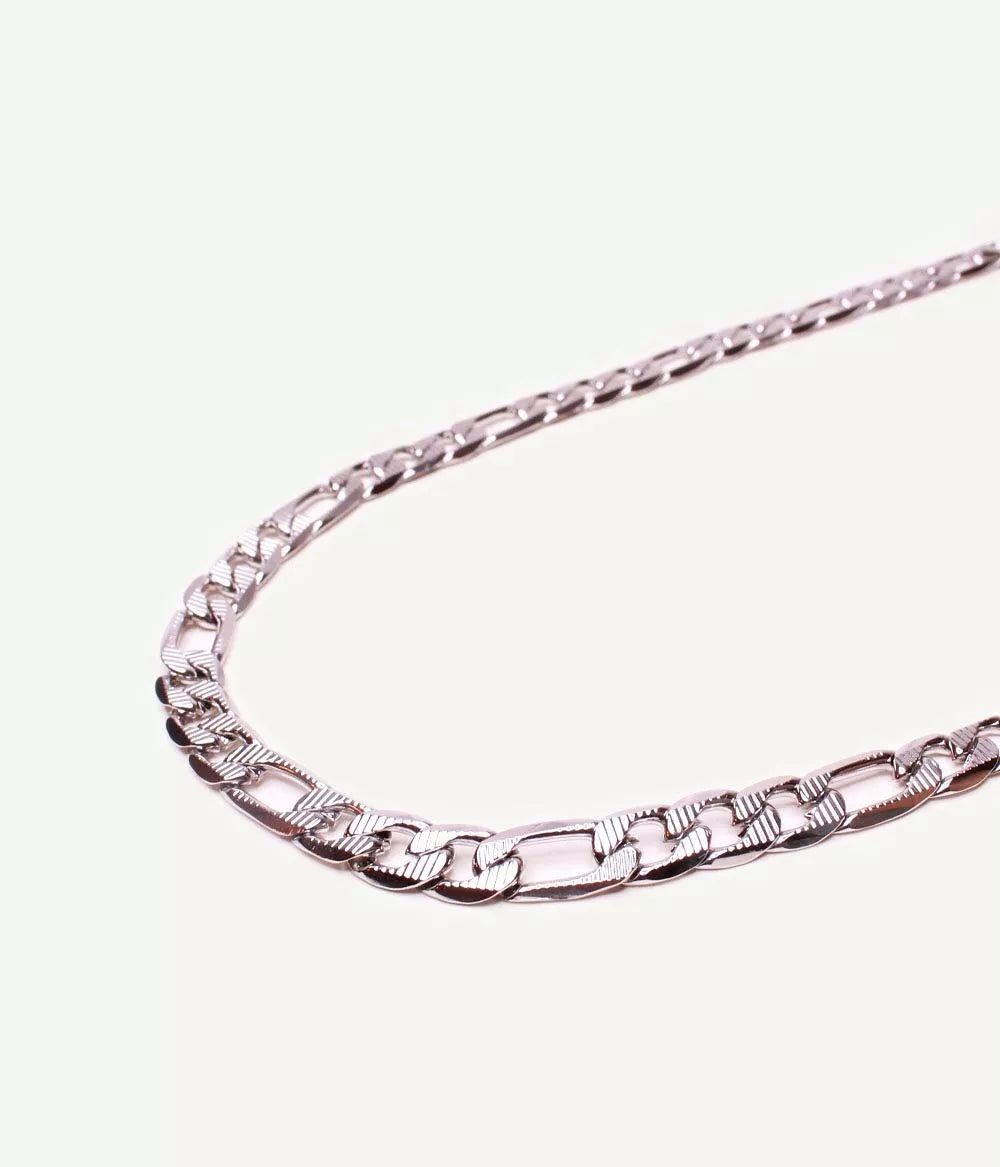 morceau arrondi de collier maille figaro argenté sur fond blanc