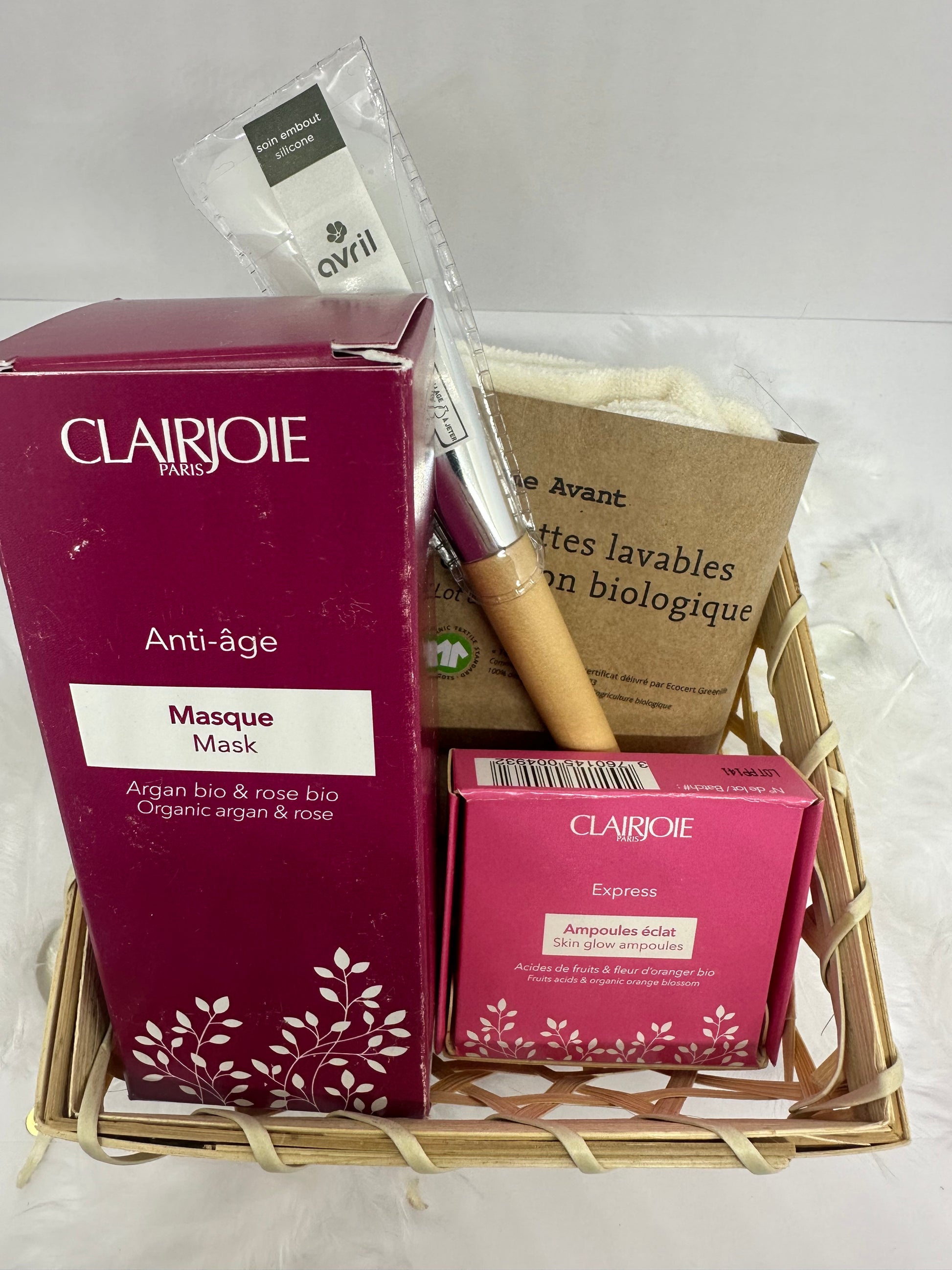 coffret rituel dans un panier en bambou couleur bois, un pinceau bout silicone manche en bois avril, un masque argan et rose clairjoie, une boite d'ampoules clairjoie et un lot de lingettes bio coton comme avant sur fond blanc et plumes blanches