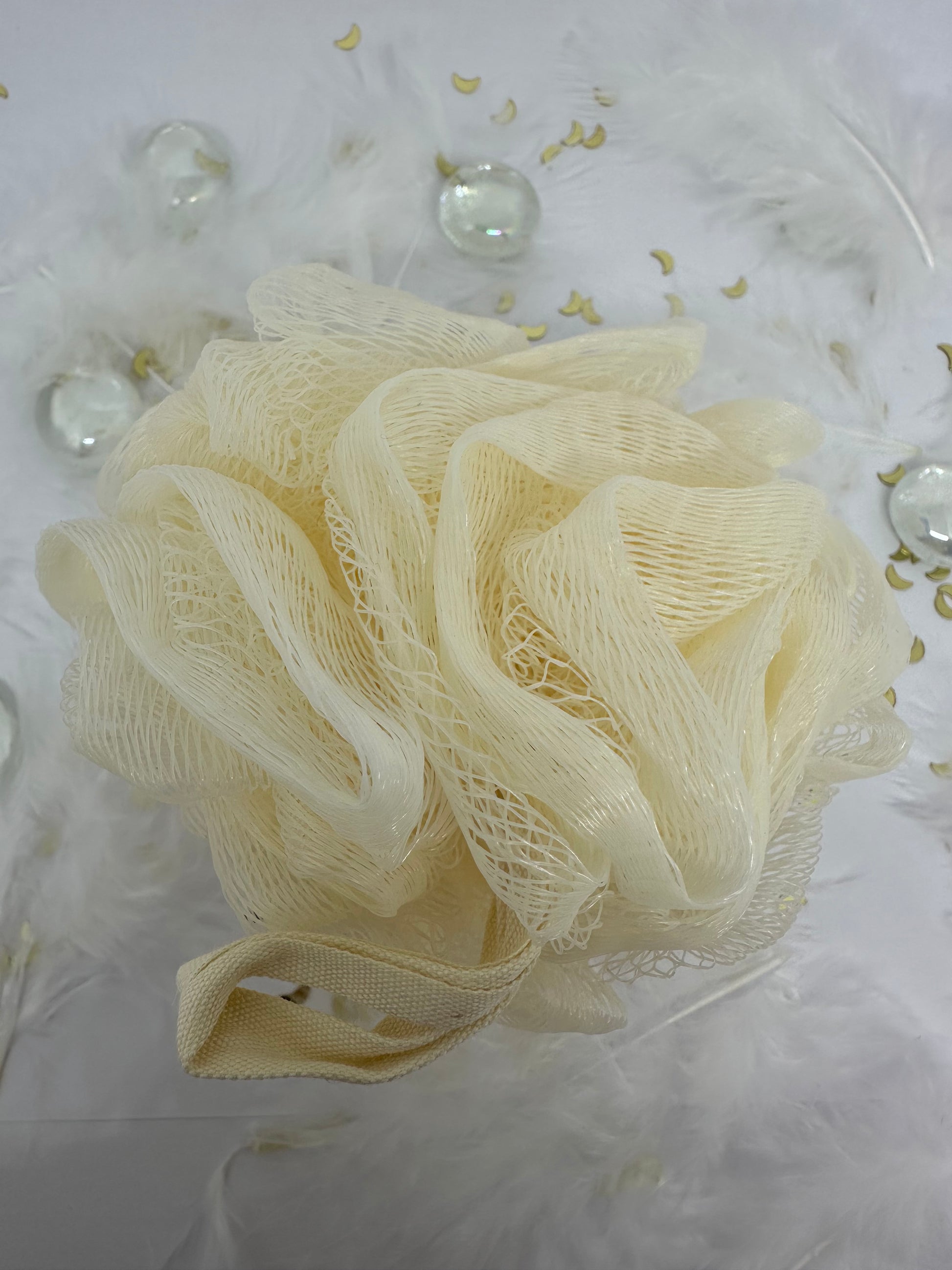 fleur de bain écrue sur fond blanc avec paillettes dorées, plumes blanches et billes transparentes