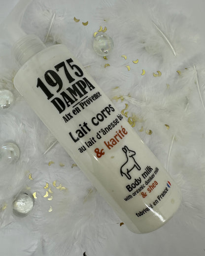lait corps anesse et karité lanc sur fond blanc avec plumes blanches, paillettes dorées et billes transparentes