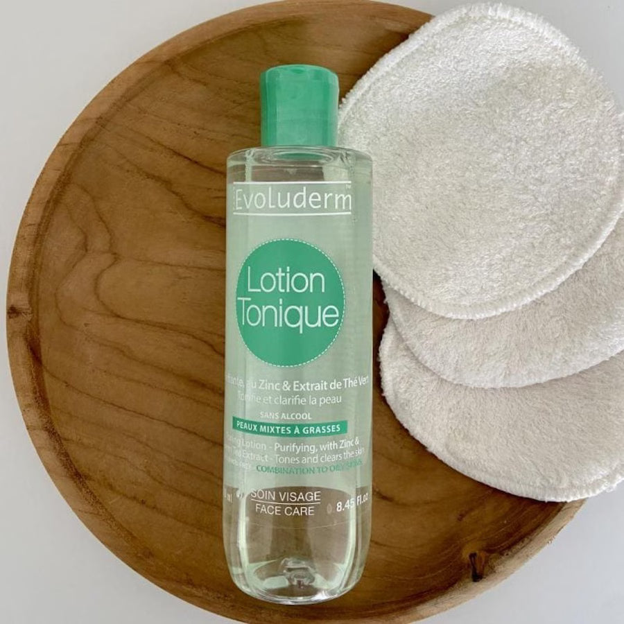 lotion tonique sur plateau en bois avec pad en coton blanc