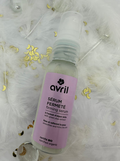 sérum fermeté avril sur fond blanc avec plumes blanches, paillettes dorées et billes transparentes
